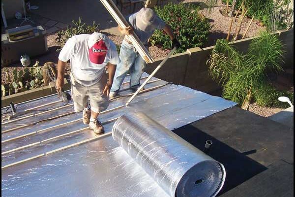 Roofers installing reflective underlaymwnt