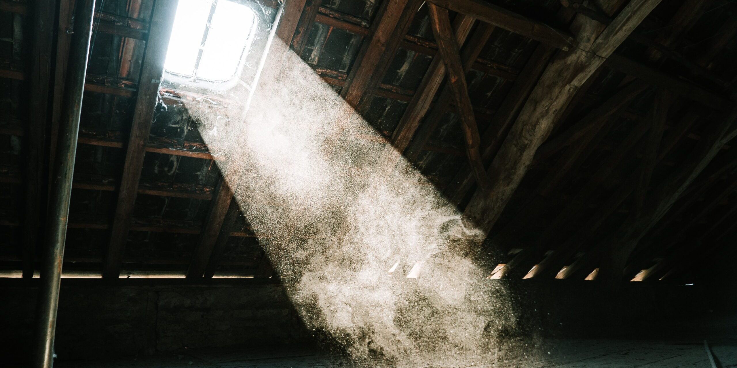 mika-baumeister-rV9m9-a5_mE-unsplash Light shining through a skylight into an attic.