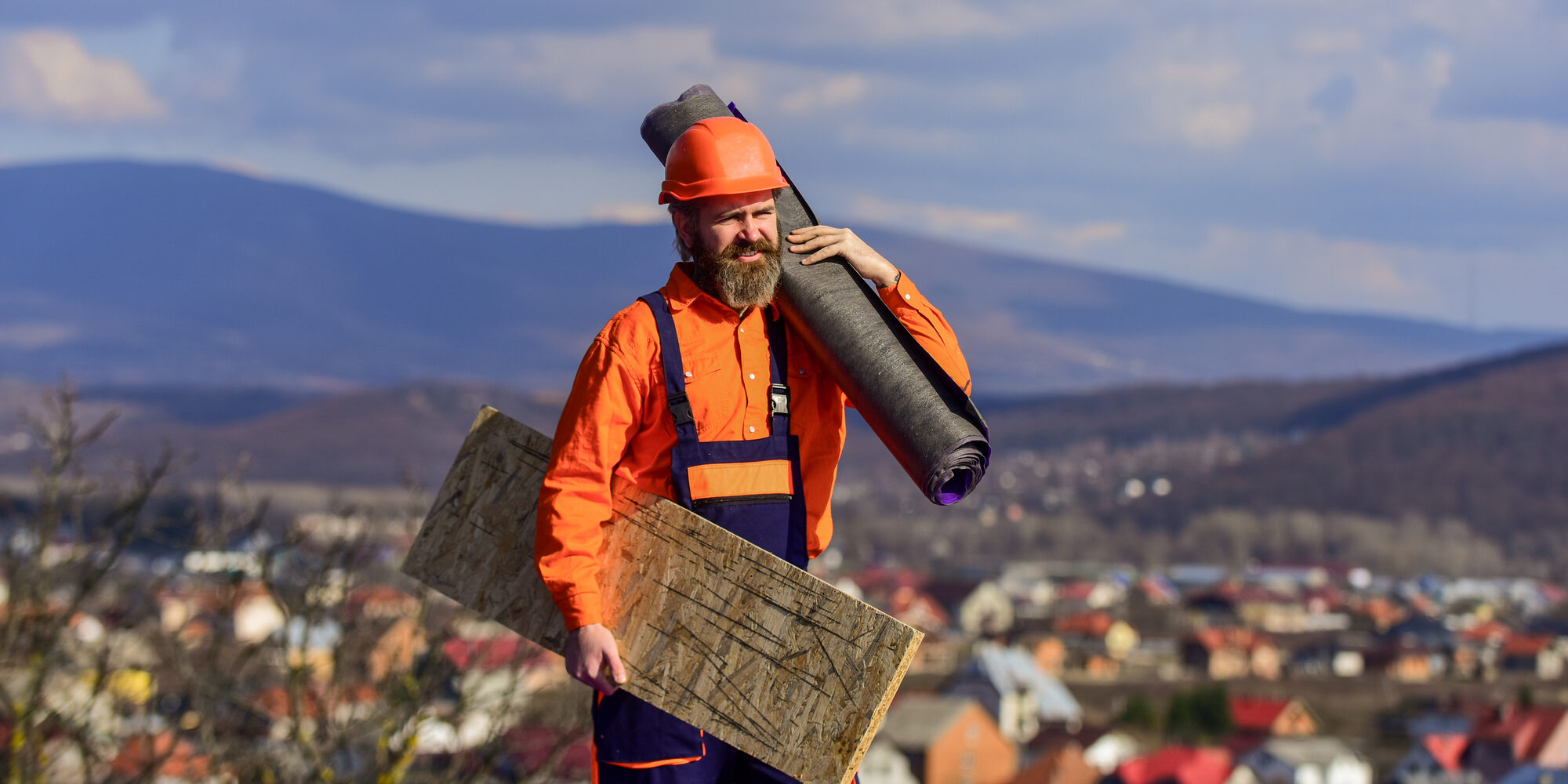man roofer inspecting damaged roof. Qualified builder installing roof tile. construction work with roofing felt. roof industrial. Roofer contractor laying rooftop with protective helmet. sunny day man in hard hat carrying roofing supplies