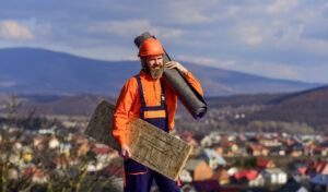man in hard hat carrying roofing supplies