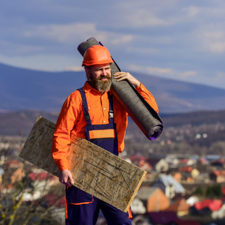 man roofer inspecting damaged roof. Qualified builder installing roof tile. construction work with roofing felt. roof industrial. Roofer contractor laying rooftop with protective helmet. sunny day man in hard hat carrying roofing supplies