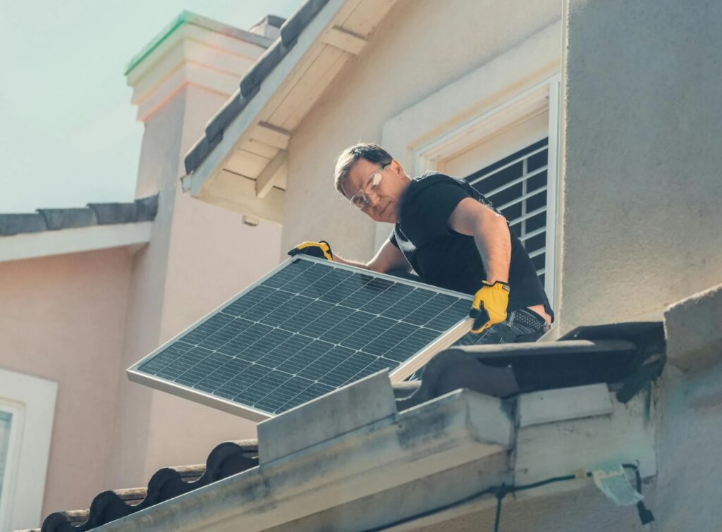 Man on tile roof holding solar panel