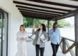 2 women and man beneath overhang roof, walking, looking up