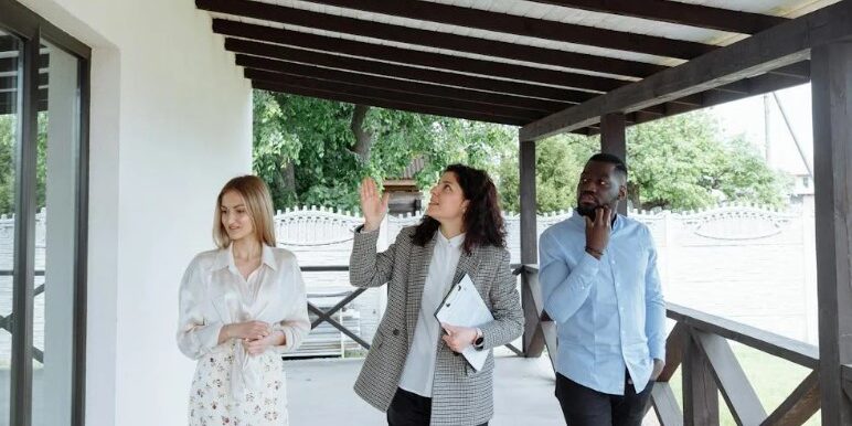 2 women and man beneath overhang roof, walking, looking up