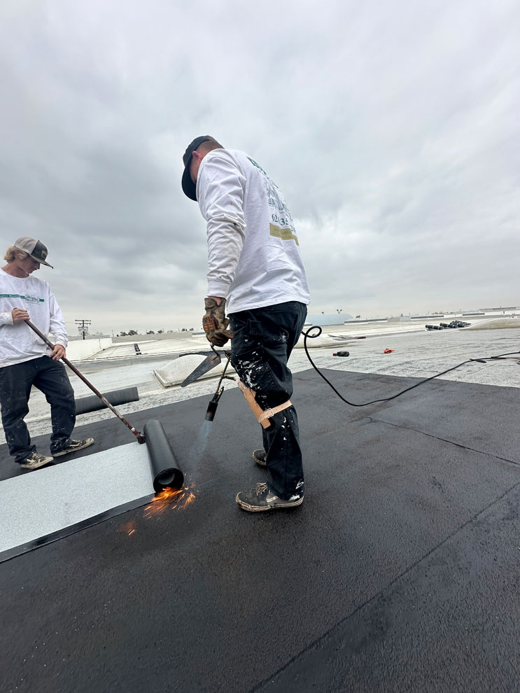 Two men installing a roof on a commercial building.