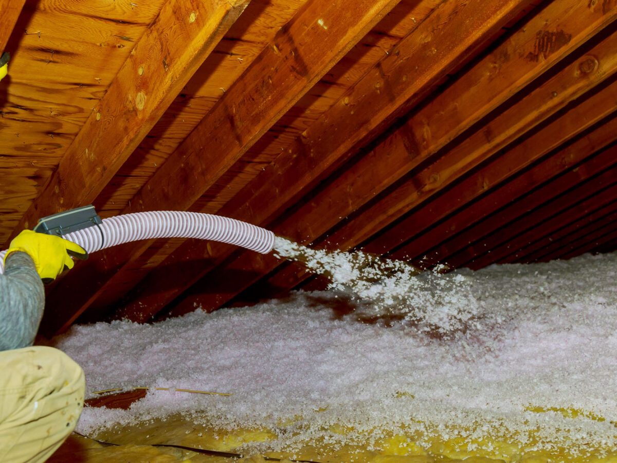 Man holding a blow-in fiberglass insulation on the attic floor.
