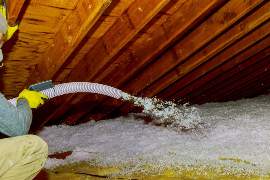 Man holding a blow-in fiberglass insulation on the attic floor.