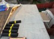 Very beginnings of a roof install with plastic tarp and roofing materials shown.