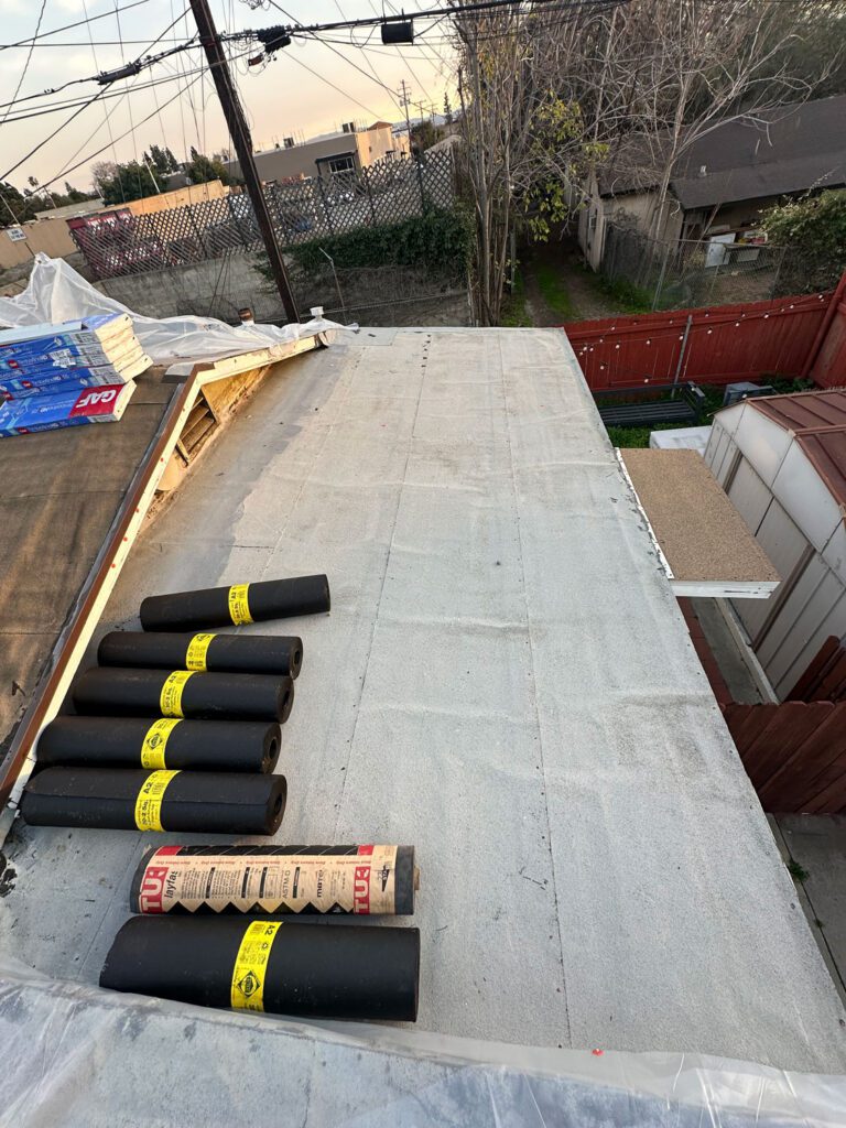 Very beginnings of a roof install with plastic tarp and roofing materials shown.