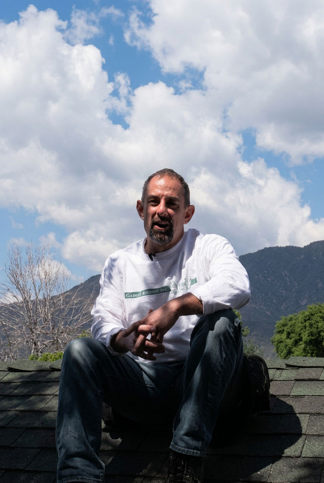 Thomas Garvey, owner of Garvey Roofing sitting on a roof.